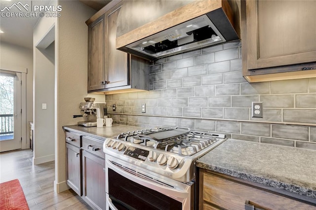 kitchen with light wood-type flooring, extractor fan, double oven range, and tasteful backsplash