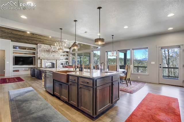kitchen featuring a textured ceiling, dark brown cabinets, a sink, open floor plan, and recessed lighting