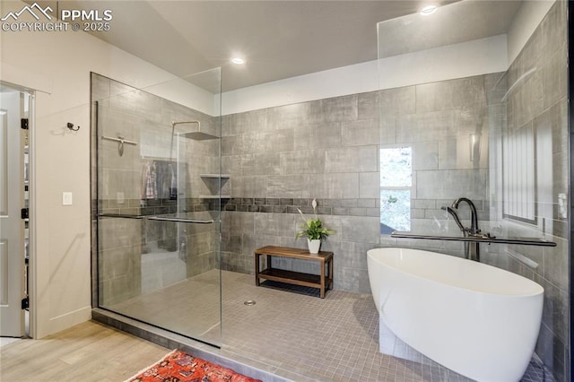 bathroom featuring a freestanding tub, recessed lighting, tiled shower, and wood finished floors