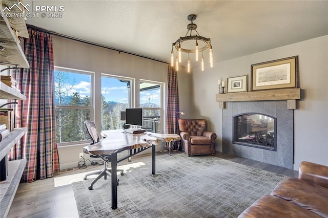 office featuring an inviting chandelier, wood finished floors, and a tile fireplace