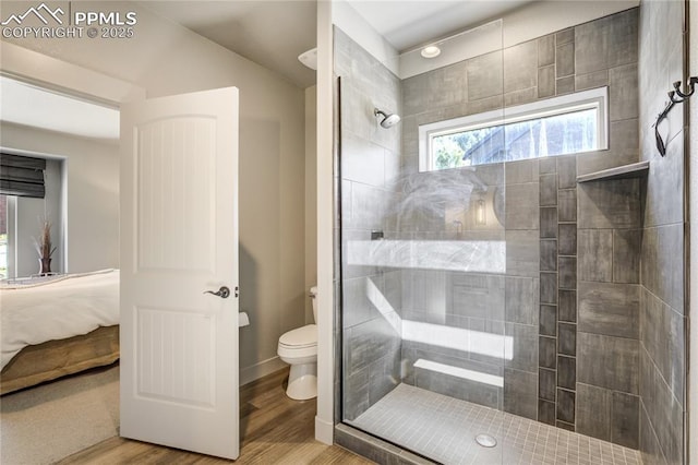 ensuite bathroom with a tile shower, toilet, wood finished floors, and connected bathroom