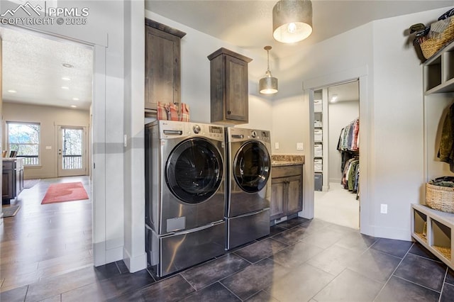washroom featuring cabinet space, baseboards, and washer and dryer