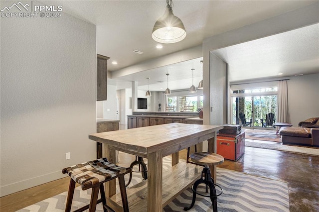 dining room featuring baseboards, a textured wall, and a healthy amount of sunlight