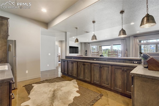 kitchen featuring dark brown cabinetry, visible vents, plenty of natural light, and open floor plan
