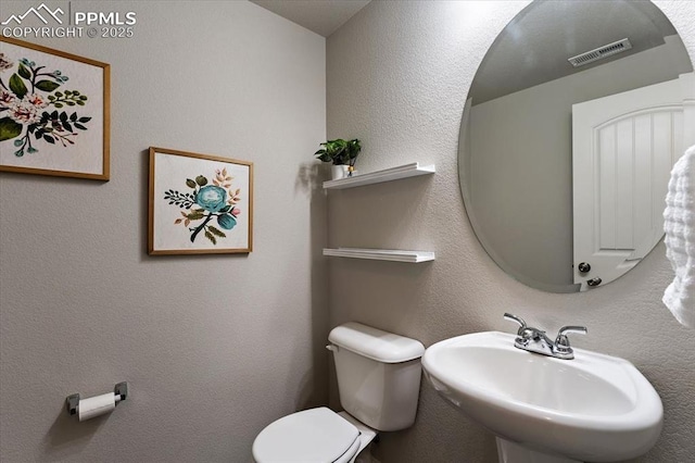 bathroom featuring toilet, visible vents, and a sink