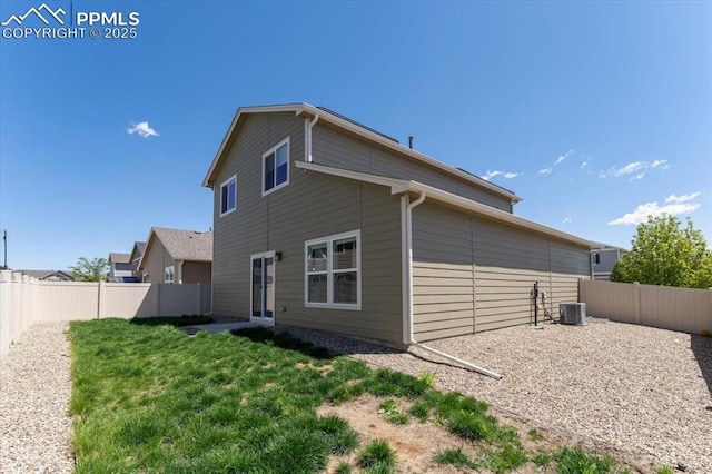 rear view of house with a fenced backyard, a yard, and cooling unit