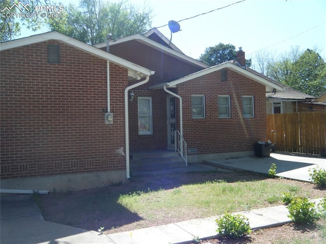 415 Veta Ave, Pueblo, CO 81004 - view of property exterior featuring brick siding, fence, and a chimney