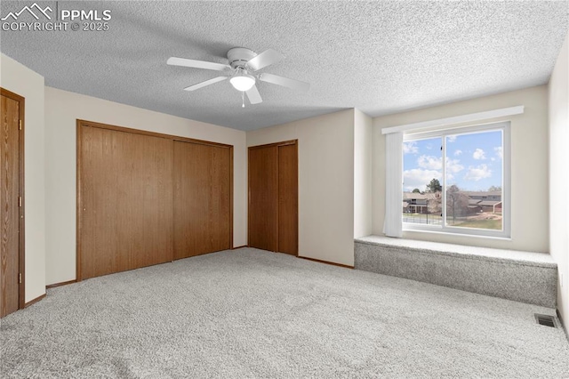 unfurnished bedroom with carpet, a ceiling fan, a textured ceiling, and visible vents