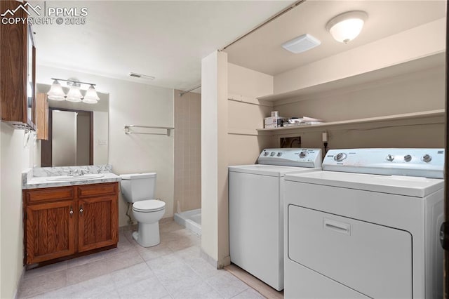 bathroom with washing machine and clothes dryer, vanity, toilet, visible vents, and a stall shower