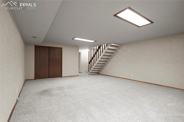 finished basement featuring baseboards, carpet flooring, stairs, and a textured wall