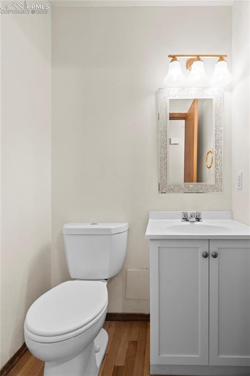 bathroom featuring toilet, baseboards, wood finished floors, and vanity