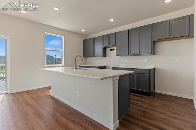 9803 Blaurock Dr, Fountain, CO 80817 - kitchen featuring baseboards, a sink, dark wood-style flooring, and a kitchen island with sink