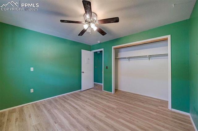 unfurnished bedroom with a ceiling fan, baseboards, wood finished floors, and a closet