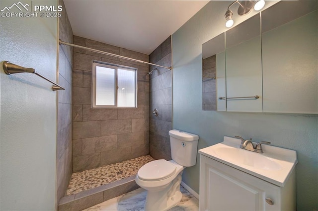 full bath with vanity, a tile shower, and toilet