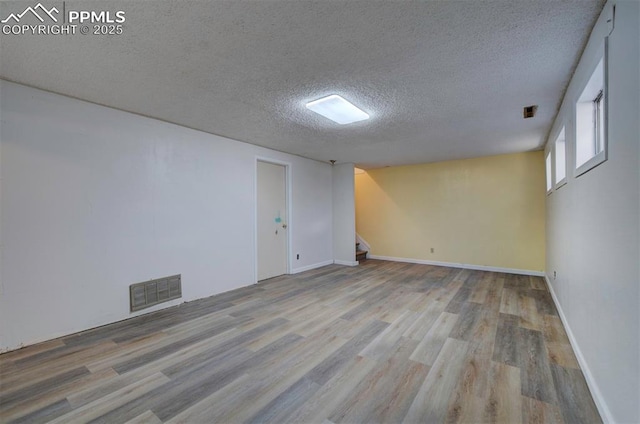 unfurnished room with visible vents, stairs, wood finished floors, baseboards, and a textured ceiling