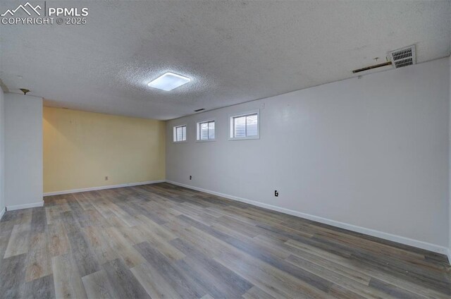 below grade area with baseboards, a textured ceiling, and wood finished floors