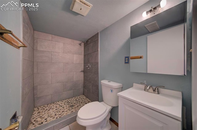 bathroom with toilet, visible vents, tiled shower, and vanity