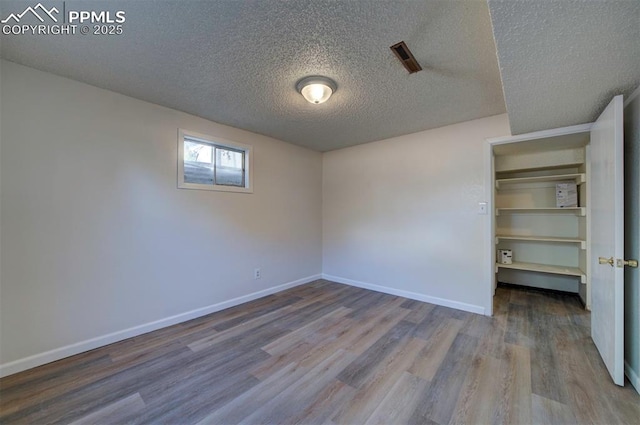 unfurnished bedroom featuring baseboards, a textured ceiling, and wood finished floors