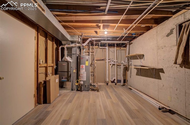 unfinished below grade area with heating unit, wood finished floors, and water heater