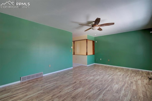 spare room with baseboards, ceiling fan, visible vents, and wood finished floors
