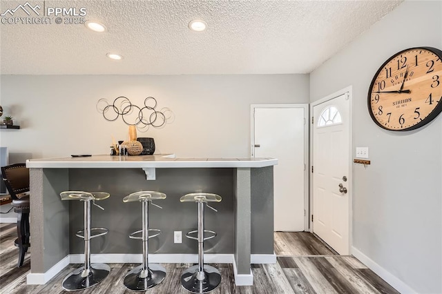 entryway with a textured ceiling, wood finished floors, baseboards, and recessed lighting