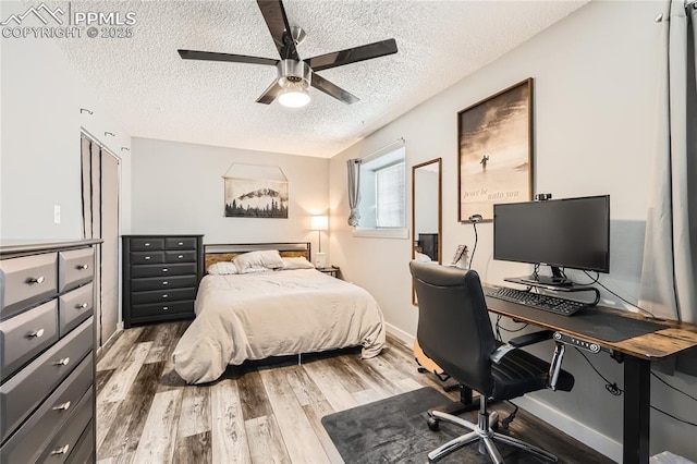 bedroom with a textured ceiling, baseboards, wood finished floors, and a ceiling fan