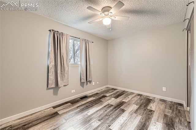 empty room featuring baseboards, ceiling fan, a textured ceiling, and wood finished floors