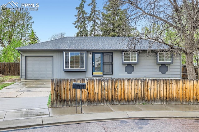 ranch-style home featuring an attached garage, a fenced front yard, driveway, and roof with shingles