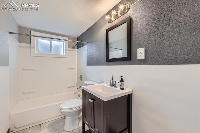 full bath featuring toilet, vanity, tile patterned flooring, washtub / shower combination, and a textured wall