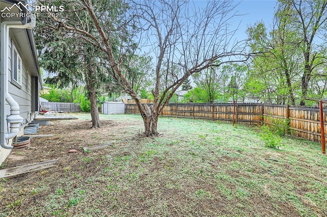 view of yard featuring a fenced backyard, a storage shed, and an outbuilding