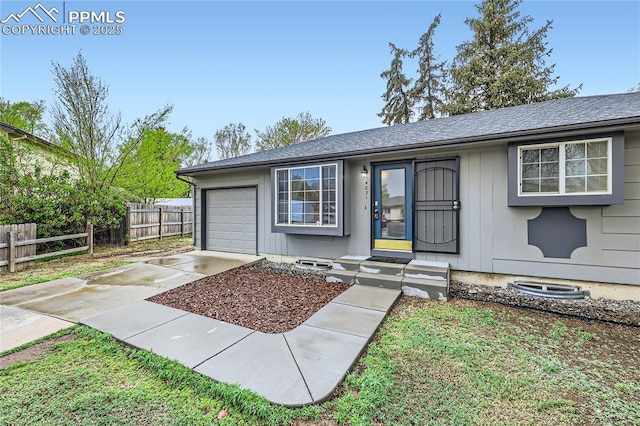 view of front of home featuring concrete driveway, a shingled roof, fence, and a garage