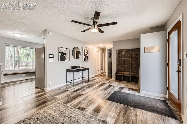 foyer with a textured ceiling, baseboards, a ceiling fan, and wood finished floors
