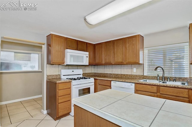kitchen featuring brown cabinetry, a sink, light tile patterned floors, and white appliances