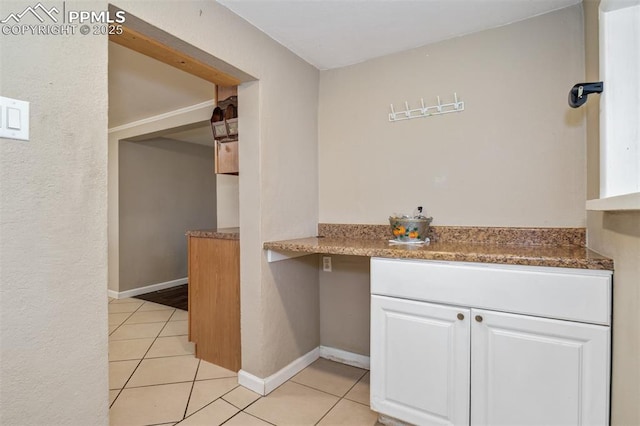 kitchen with light tile patterned floors, baseboards, and white cabinetry