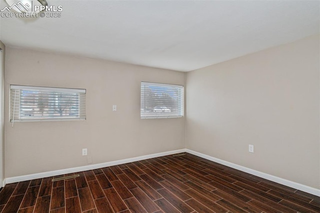 empty room featuring baseboards, a healthy amount of sunlight, and wood finished floors