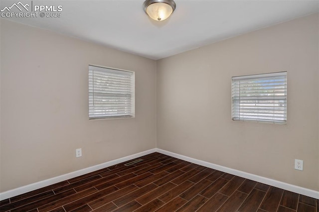 spare room with baseboards and wood finished floors