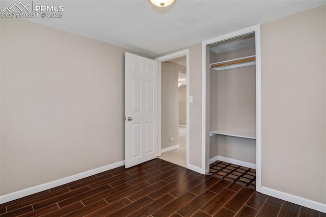 unfurnished bedroom featuring baseboards, wood finished floors, and a closet