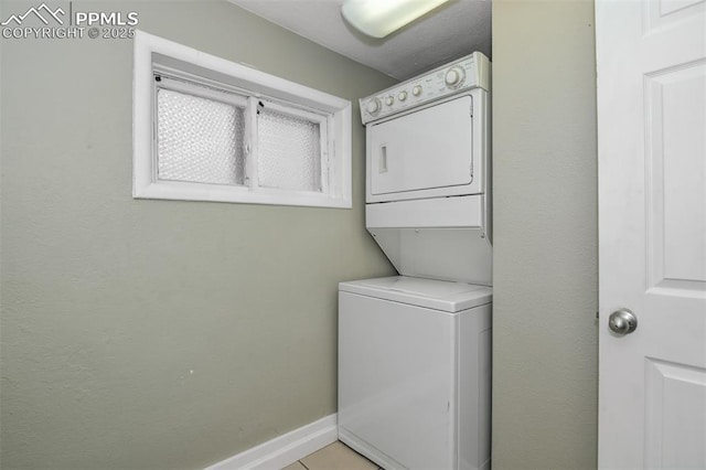 clothes washing area featuring laundry area, stacked washing maching and dryer, and baseboards