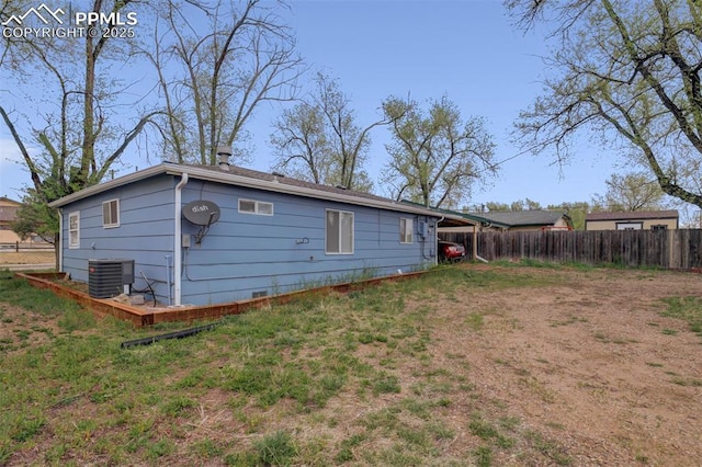 rear view of house with central AC unit, fence, and a carport