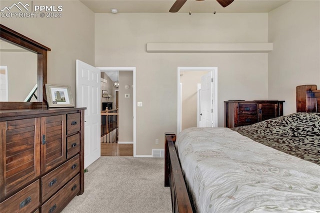 carpeted bedroom with visible vents, connected bathroom, baseboards, and ceiling fan