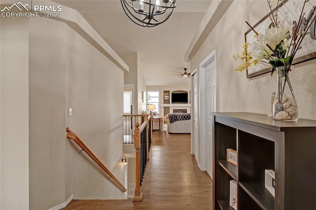 hall with a chandelier, wood finished floors, and an upstairs landing