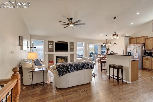 living room with light wood-style flooring, a wealth of natural light, and ceiling fan with notable chandelier