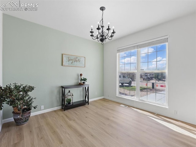 unfurnished dining area featuring baseboards, wood finished floors, a notable chandelier, and visible vents