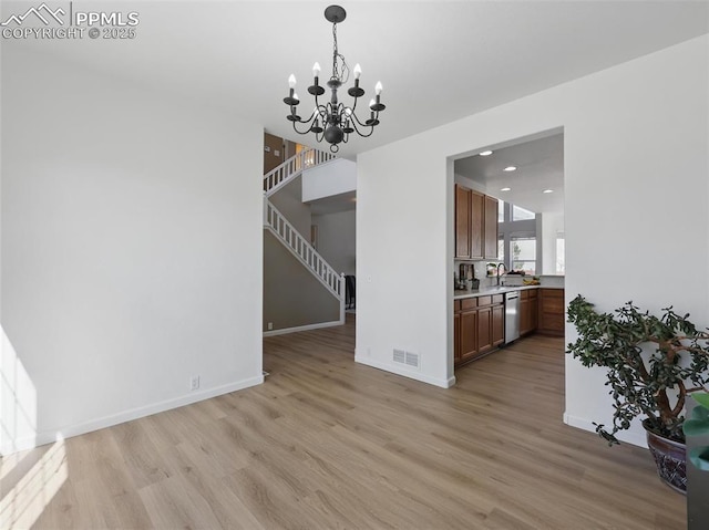 unfurnished dining area featuring a chandelier, baseboards, visible vents, and light wood-style flooring