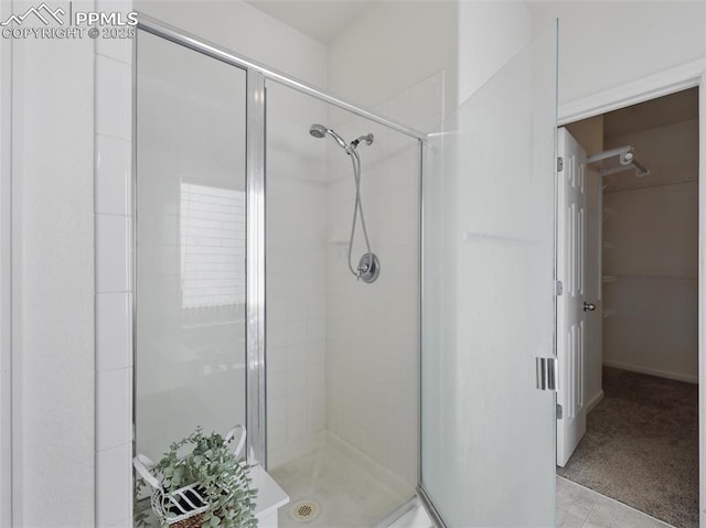 full bath with a walk in closet and a stall shower