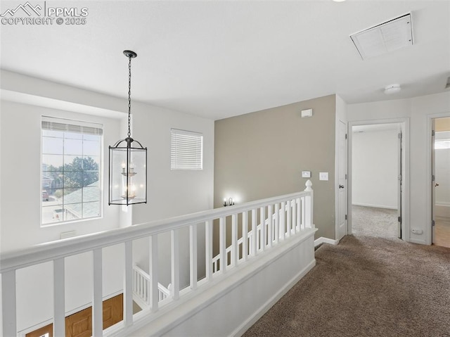 hall featuring visible vents, baseboards, an upstairs landing, an inviting chandelier, and carpet