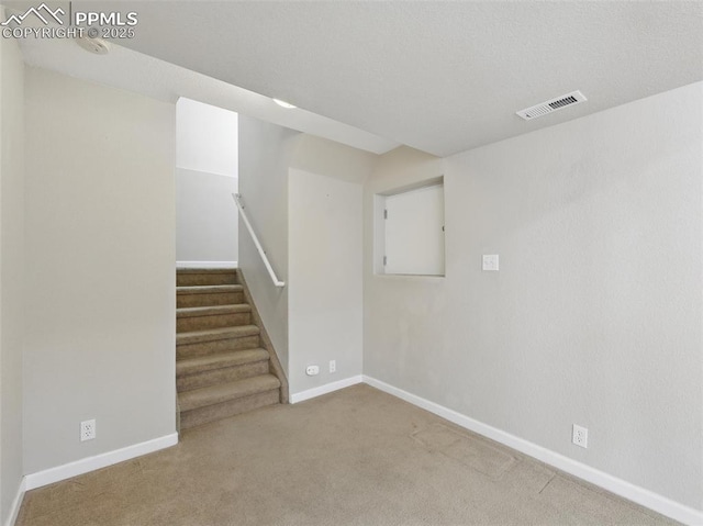 basement featuring carpet floors, baseboards, stairs, and visible vents