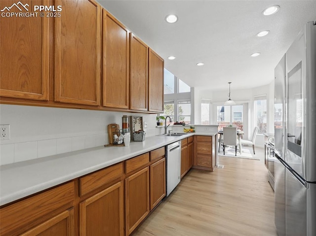 kitchen featuring a sink, dishwasher, plenty of natural light, brown cabinetry, and smart refrigerator