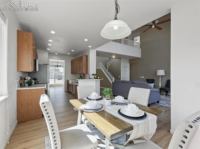 dining room featuring recessed lighting, ceiling fan with notable chandelier, light wood-type flooring, and stairs