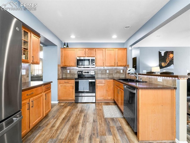 5346 Gentle Wind Rd, Colorado Springs, CO 80922 - kitchen with appliances with stainless steel finishes, a sink, a peninsula, dark wood-style flooring, and decorative backsplash